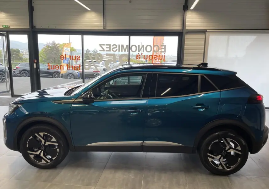 Profil côté gauche du Peugeot 2008 hybride bleu avec jantes alliage 17'' bi-ton et barres de toit noir brillant.