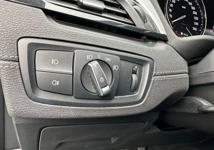 Gros plan sur le tableau de bord gris du BMW X2 2018, montrant les commandes d'éclairage et le compteur de vitesse.
