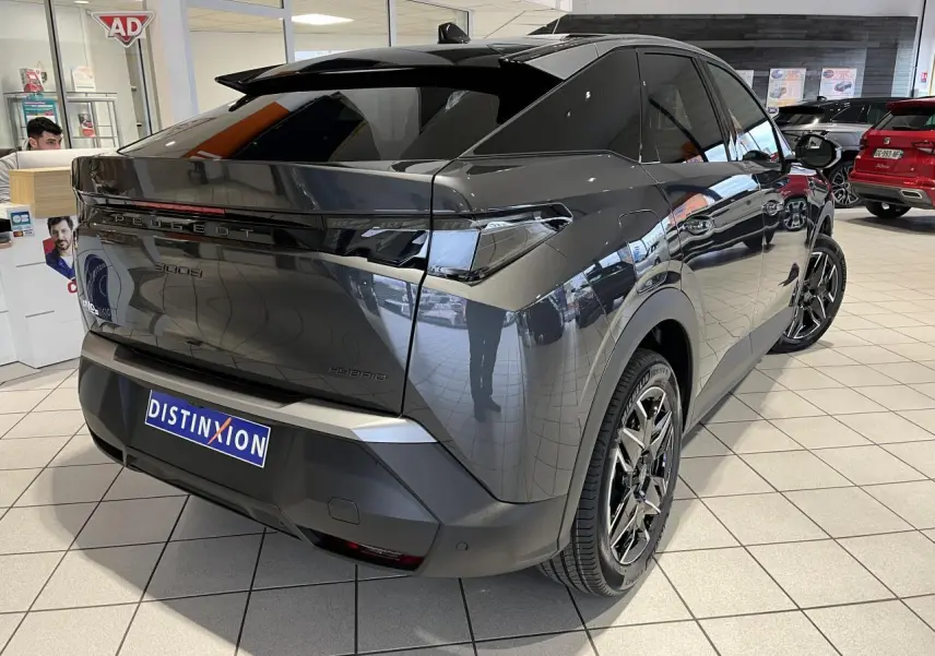 Vue 3/4 arrière droite du Peugeot 3008 Hybrid gris titanium avec jantes alliage 19'' et bandeau noir laqué entre feux arrière.