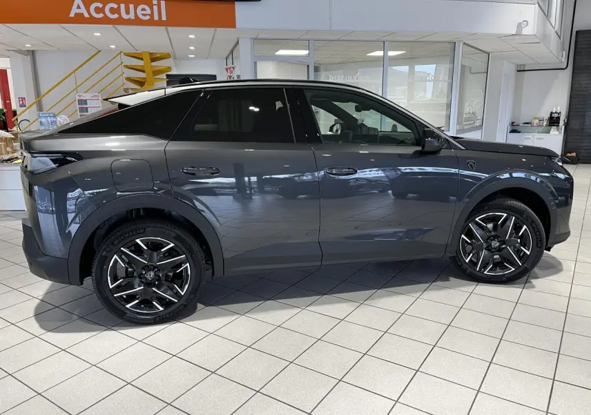 Profil droit d’un Peugeot 3008 gris titanium 2025 en hybride essence, avec jantes alliage 19 pouces et toit noir.
