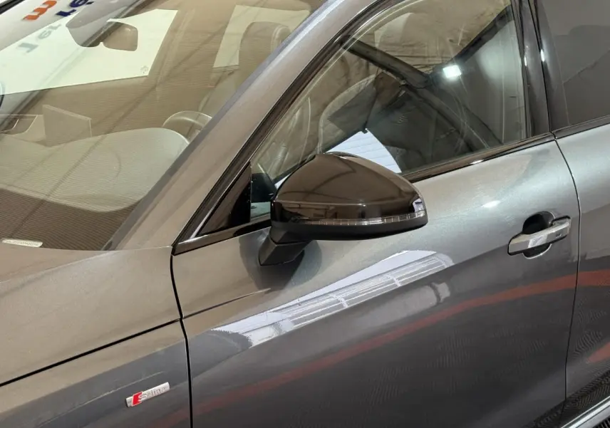 Vue rapprochée du côté gauche d’une Audi A4 gris foncé avec rétroviseur noir et badge S line visible sur la portière.
