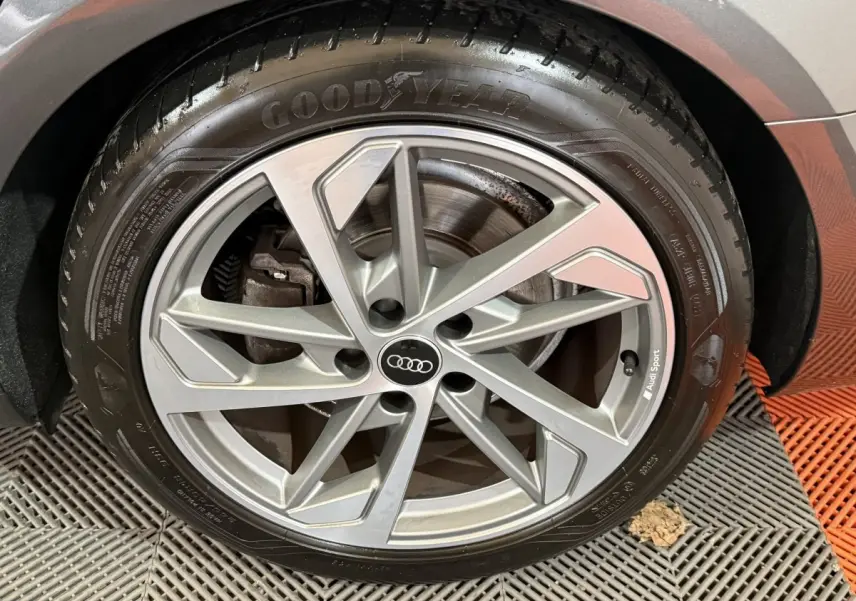 Gros plan sur la jante alliage argentée Audi Sport et pneu Goodyear d'une Audi A4 gris foncé.