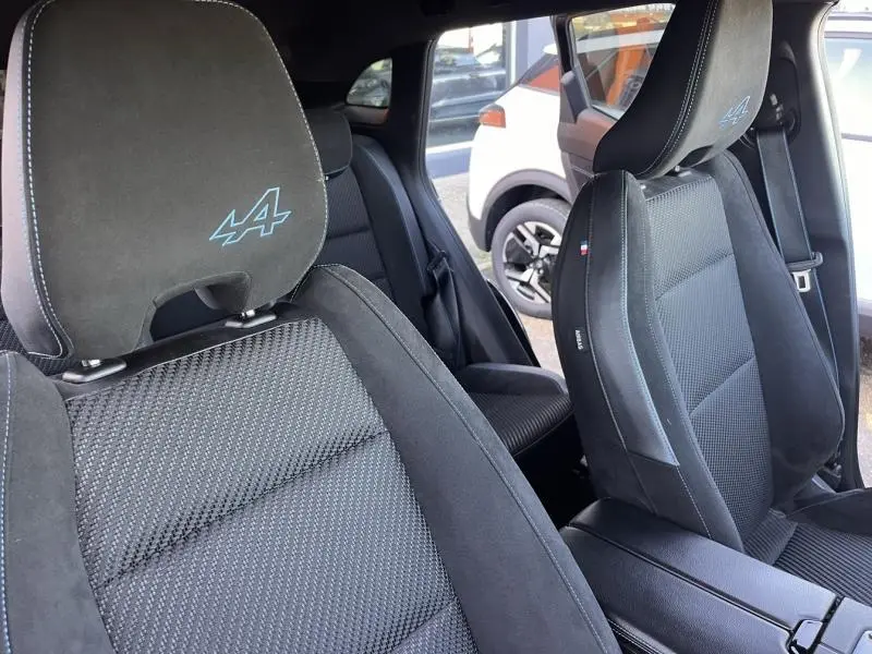 Gros plan sur les sièges avant noirs en tissu carbone et alcantara du Renault Austral 2023, logo Alpine brodé sur les appuie-têtes.