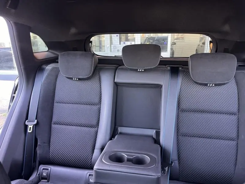 Vue intérieure arrière du Renault Austral 2023, sièges noirs en tissu carbone/Alcantara avec accoudoir central et porte-gobelets.