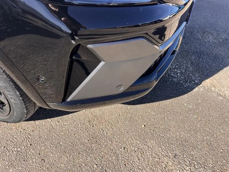 Gros plan sur l'angle avant droit noir étoilé du Renault Austral 1.2 E-Tech avec détails du pare-chocs et capteur de stationnement.