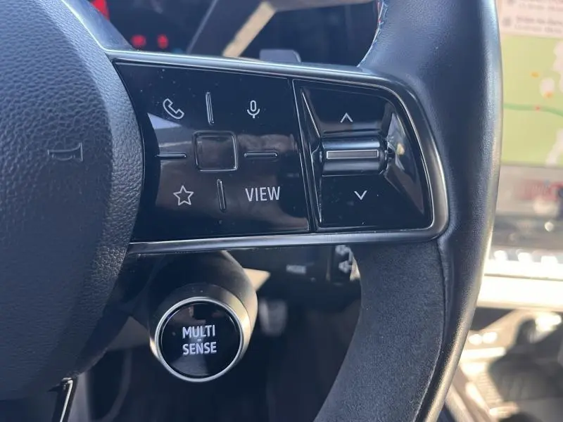 Gros plan sur les commandes noires du volant cuir-alcantara du Renault Austral noir étoilé, avec bouton Multi Sense visible.