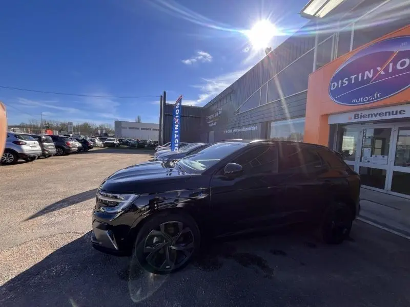Vue 3/4 avant droit d'un Renault Austral noir étoilé stationné devant un bâtiment commercial par temps ensoleillé.