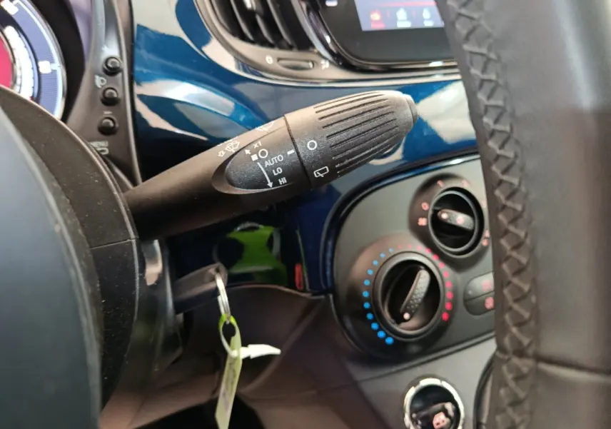 Gros plan sur la commande d’essuie-glace et les réglages de climatisation, tableau de bord bleu de la Fiat 500 Hybrid.