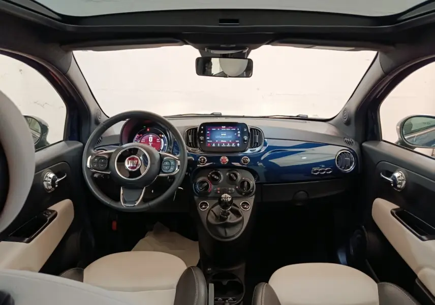 Vue intérieure avant de la FIAT 500 Hybrid 2022, tableau de bord bleu brillant avec écran tactile central et volant multifonctions.
