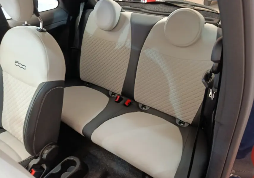 Vue intérieure arrière montrant la banquette beige et noire de la Fiat 500 Hybrid 2022 avec appuie-têtes ronds.
