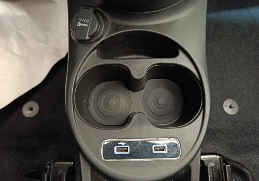 Vue rapprochée de la console centrale noire de la FIAT 500 Hybrid avec porte-gobelets et deux ports USB.