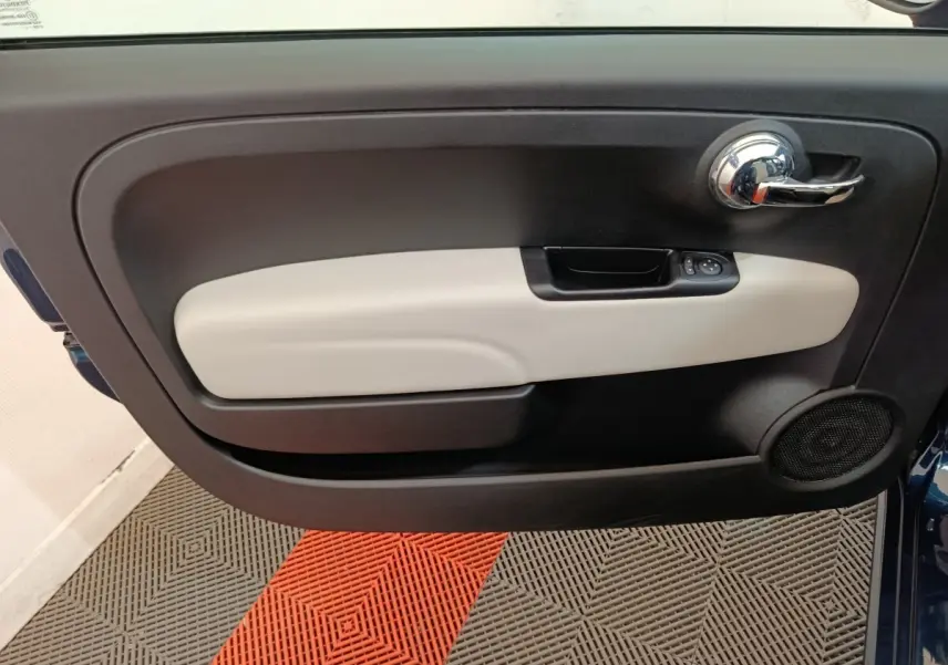 Vue intérieure du panneau de porte avant gauche de la FIAT 500 bleu, avec poignée chromée et commande de vitres.