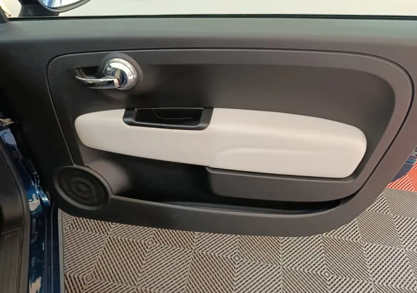 Vue rapprochée de la porte avant gauche bleu de la FIAT 500 Dolcevita avec insert beige et poignée chromée.