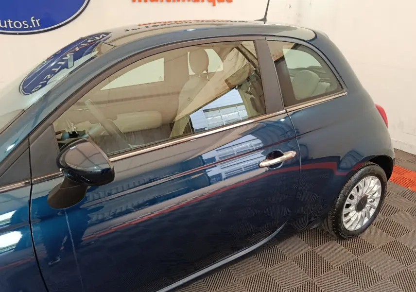 Vue latérale droite d'une FIAT 500 Dolcevita hybride bleu métallisé, avec jantes alliage et rétroviseur assorti.