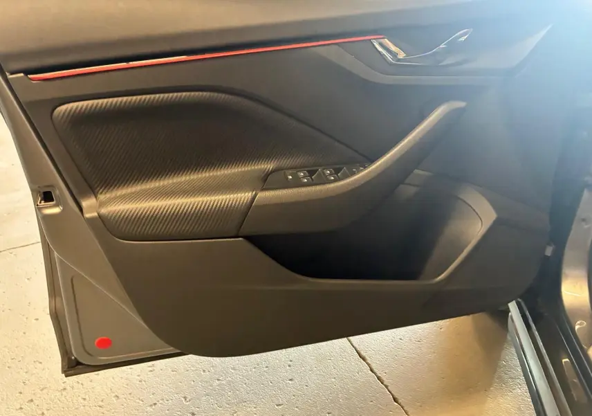 Vue intérieure côté gauche de la porte avant d'une Skoda Kamiq gris foncé, avec insert texturé et commandes de vitres.