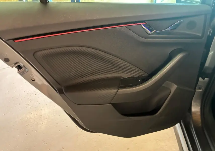 Vue intérieure de la porte avant gauche du Skoda Kamiq 2024 gris foncé, avec insert décoratif rouge et finition noire.
