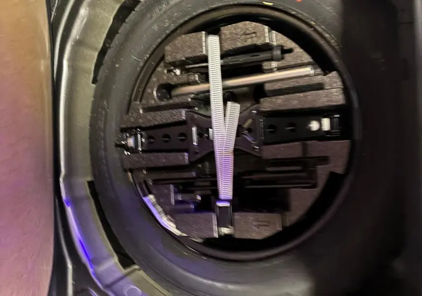 Vue rapprochée de la roue de secours et des outils de bord dans le coffre d'un Skoda Kamiq gris foncé 2024.