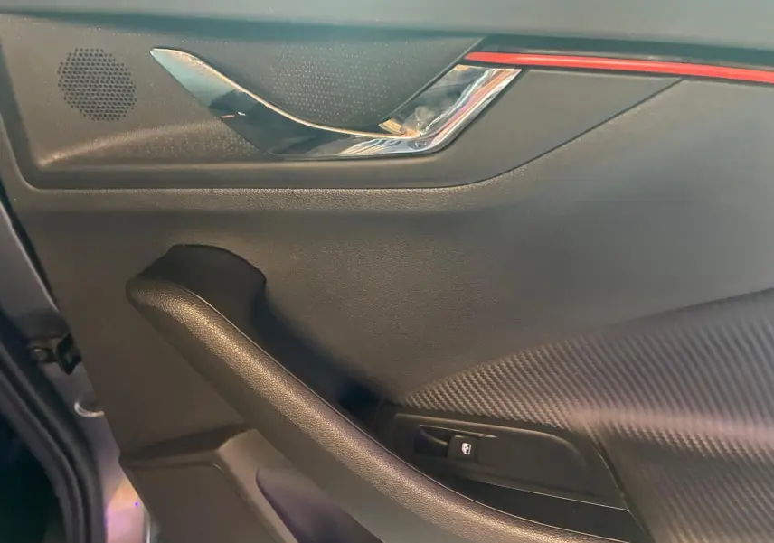 Détail de la porte intérieure côté conducteur du Skoda Kamiq 2024 gris foncé, avec poignée chromée et bouton de verrouillage.