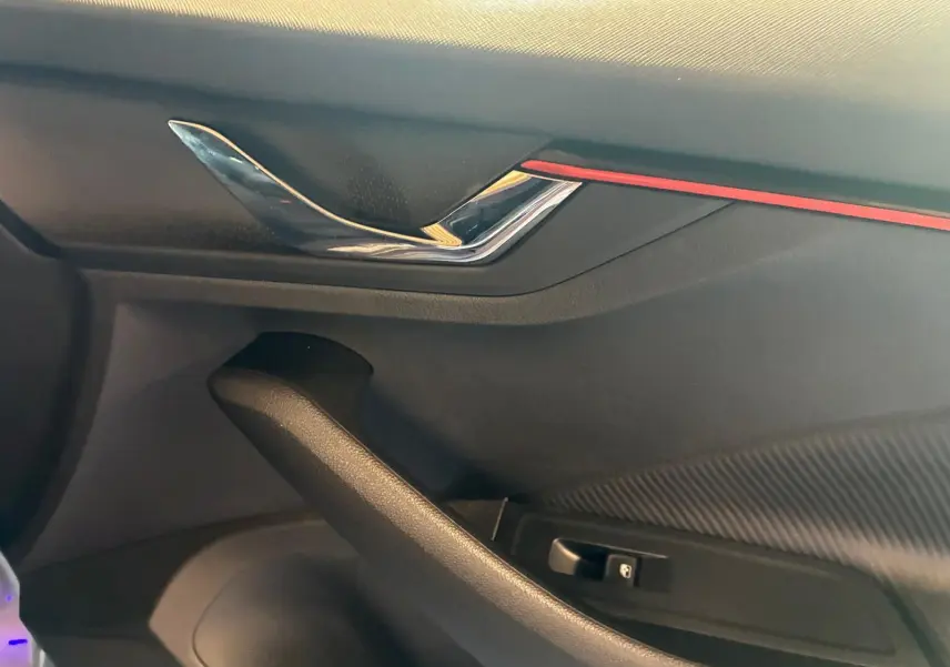Détail de la poignée intérieure côté conducteur du Skoda Kamiq 2024 gris foncé avec insert rouge et finition carbone.