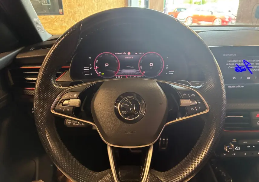 Vue centrée sur le volant perforé noir du Skoda Kamiq 2024 avec tableau de bord numérique et écran multimédia.