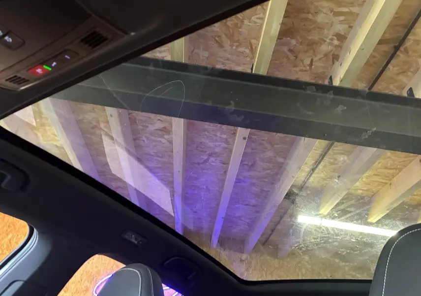 Toit panoramique en verre du Skoda Kamiq gris foncé 2024, vue intérieure vers le plafond en bois d'atelier.