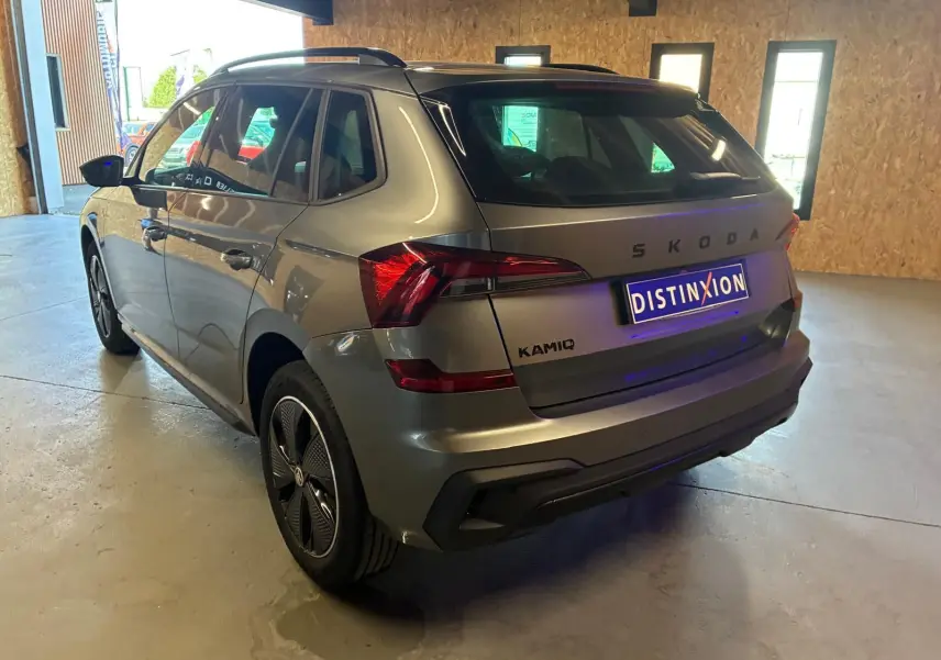 Vue 3/4 arrière droite d'un Skoda Kamiq gris foncé 2024, finition Monte-Carlo avec feux arrière LED et jantes spécifiques.