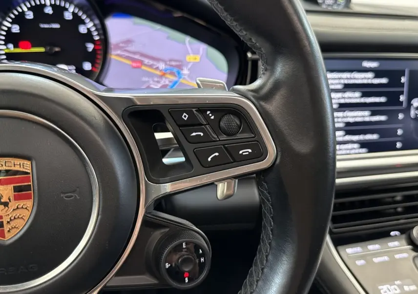 Gros plan sur le volant cuir noir multifonctions de la Porsche Panamera 4 E-Hybrid avec écran tactile et navigation visible.