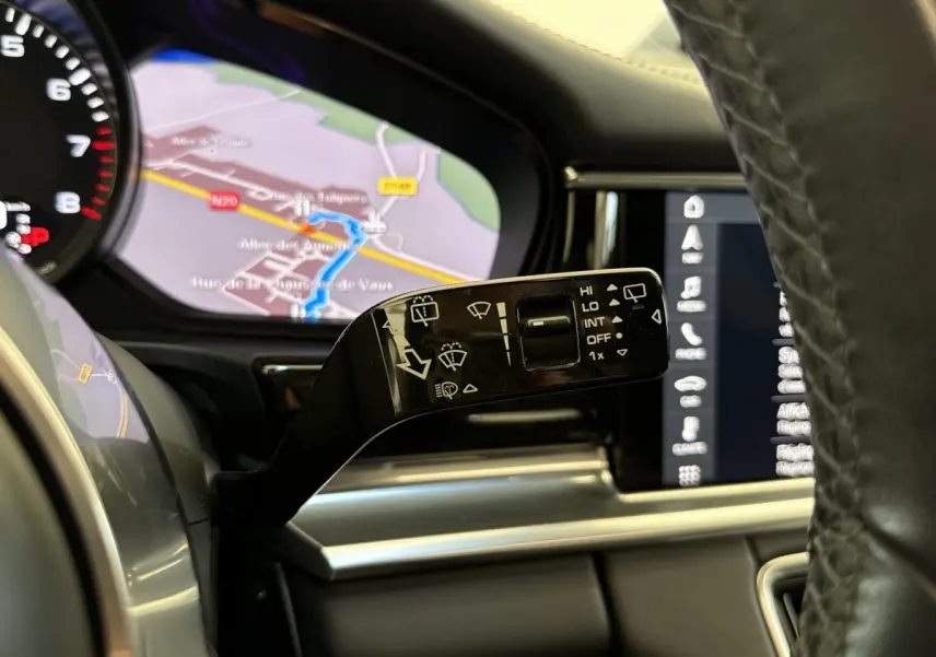 Gros plan sur la commande d’essuie-glace à gauche du volant cuir dans l’habitacle d’une Porsche Panamera 4 E-Hybrid noire.