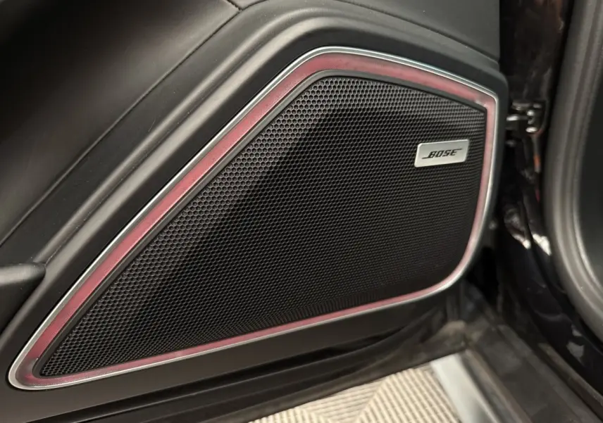 Gros plan sur le haut-parleur Bose intégré dans la porte intérieure côté conducteur d'une Porsche Panamera 4 E-Hybrid Sport Turismo noire.