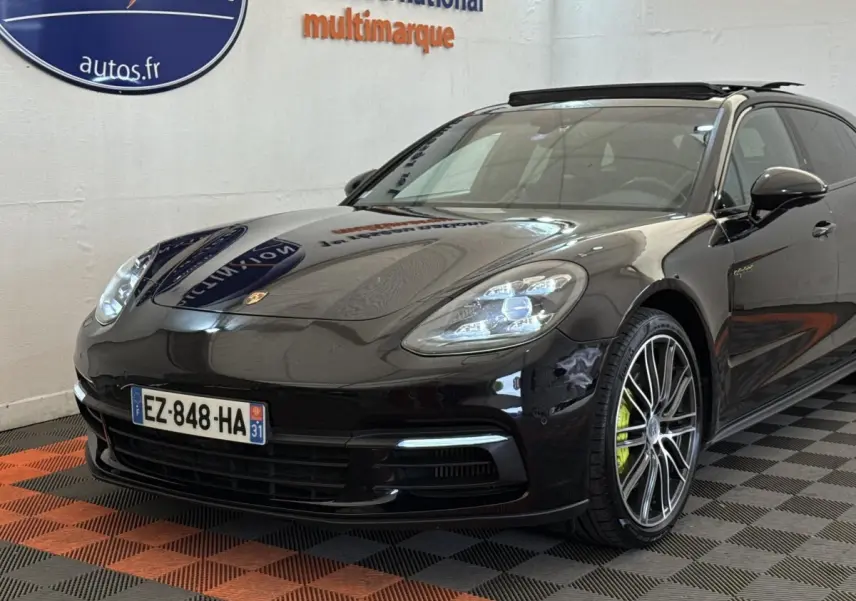Vue 3/4 avant droite d'une Porsche Panamera 4 E-Hybrid Sport Turismo noire avec jantes alliage et étriers verts.