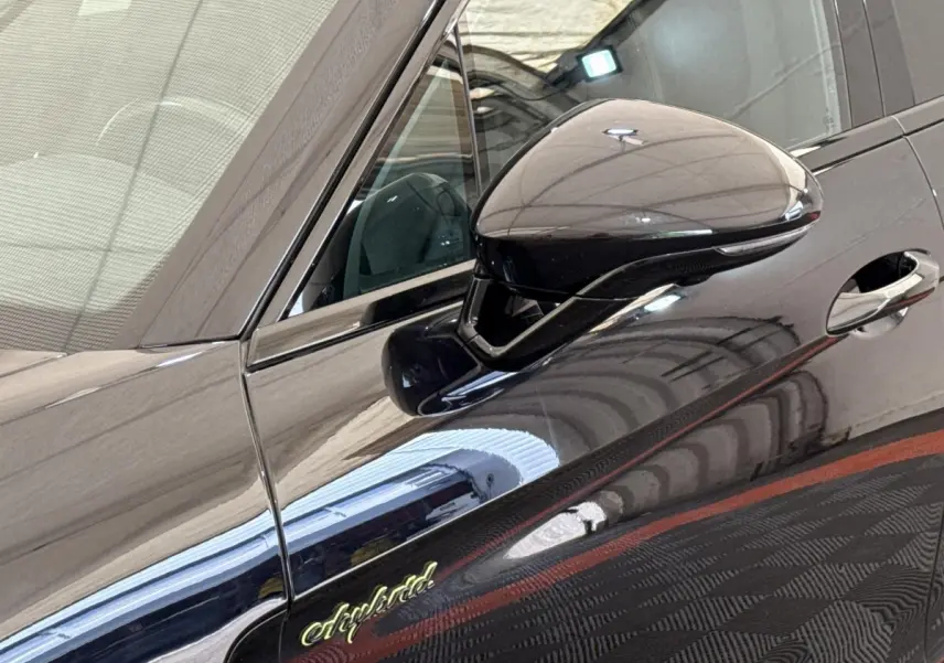 Détail du rétroviseur côté gauche et logo "e-hybrid" sur la porte d'une Porsche Panamera noire.