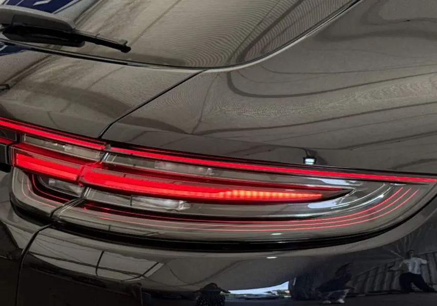 Gros plan sur le feu arrière droit rouge d’une Porsche Panamera 4 E-Hybrid Sport Turismo noire, finition brillante.