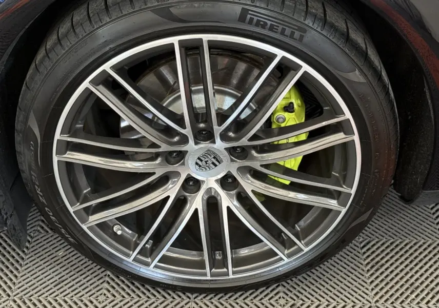 Gros plan sur la roue avant droite d'une Porsche Panamera 4 E-Hybrid noire avec étrier de frein jaune vif.