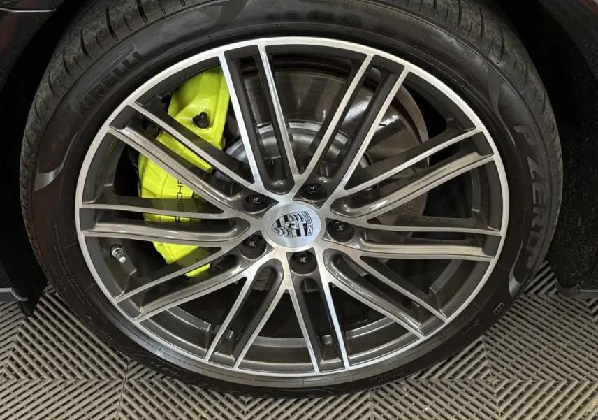 Gros plan sur la jante alliage grise et l’étrier de frein jaune vif d’une Porsche Panamera 4 E-Hybrid Sport Turismo noire.