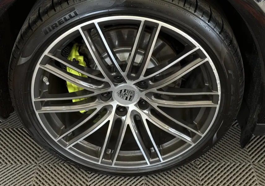 Gros plan sur la jante alliage grise et le frein jaune vif d'une Porsche Panamera 4 E-Hybrid Sport Turismo noire.