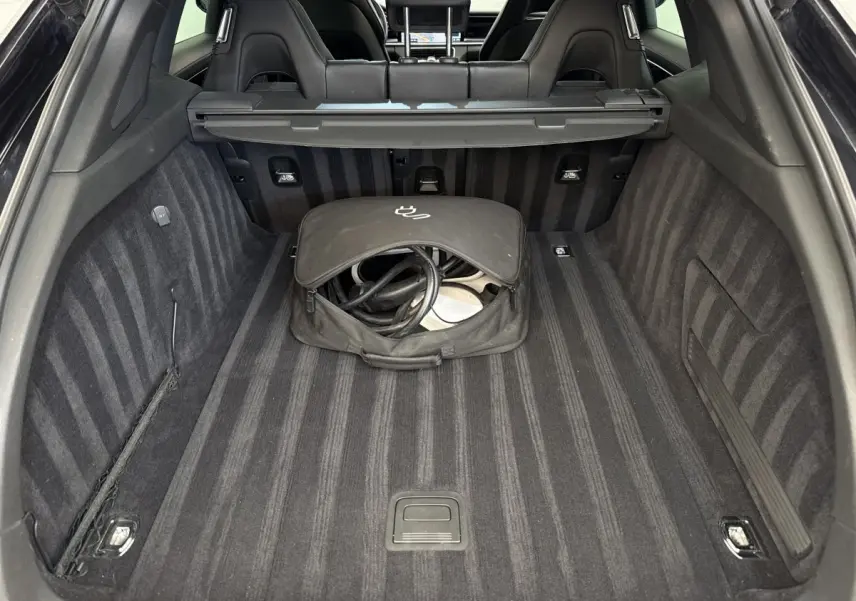 Vue du coffre arrière noir de la Porsche Panamera 4 E-Hybrid Sport Turismo avec sac de câble de recharge au centre.