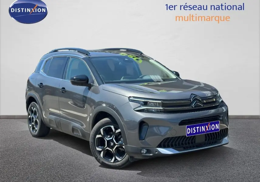 Citroën C5 Aircross gris Platinium vue 3/4 avant droit avec jantes alu et barres de toit visibles.