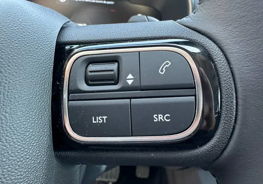 Gros plan sur les commandes noires du volant cuir du Citroën C5 Aircross 2025, finition Gris Platinium.
