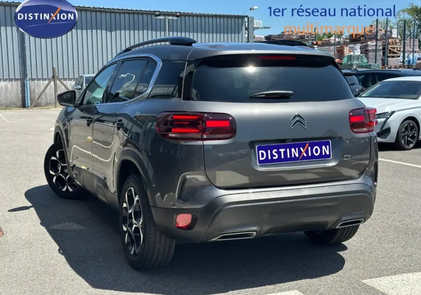 Vue 3/4 arrière droite d'un Citroën C5 Aircross gris Platinium avec feux arrière LED et jantes alu noires.