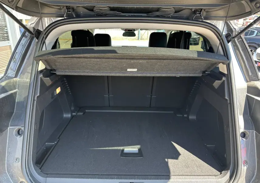 Coffre ouvert vu de l'arrière d'un Citroën C5 Aircross gris Platinium, avec cache-bagages relevé et intérieur noir.