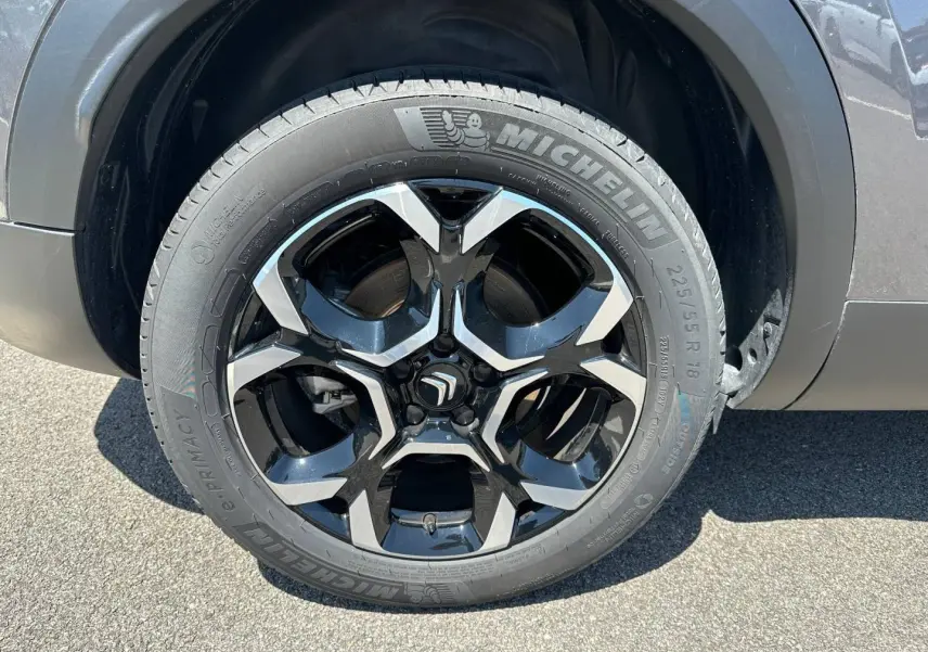 Gros plan sur la jante alu noire et argent avec pneu Michelin du côté droit d’un Citroën C5 Aircross gris Platinium.