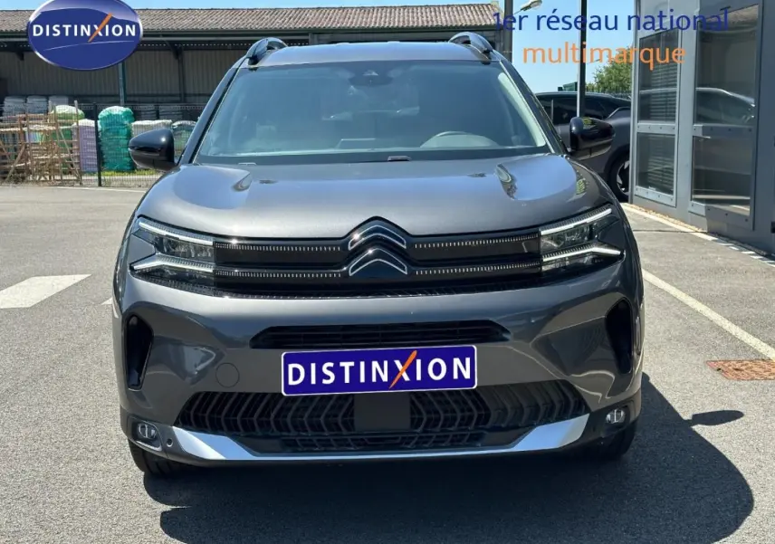 Vue frontale d'un Citroën C5 Aircross 2025 gris Platinium avec calandre distinctive et barres de toit visibles.