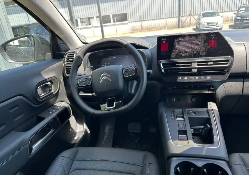 Vue intérieure côté conducteur du Citroën C5 Aircross 2025, volant cuir multifonction et écran tactile central visible.