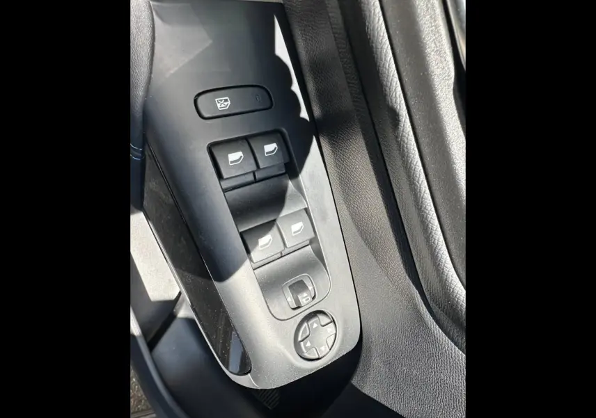 Gros plan sur les commandes de lève-vitres et rétroviseurs côté conducteur du Citroën C5 Aircross 2025 en intérieur noir.