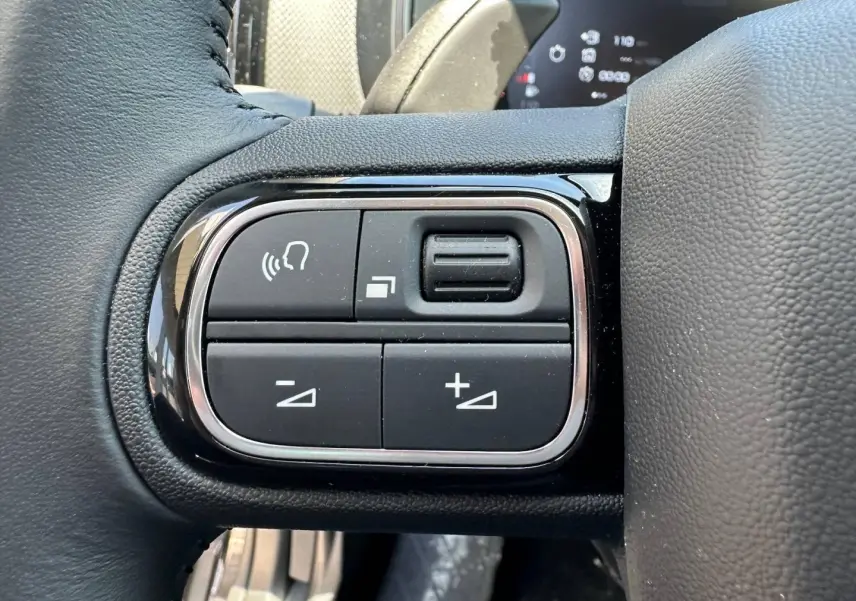 Gros plan sur les commandes vocales et de volume sur le volant cuir noir du Citroën C5 Aircross 2025.