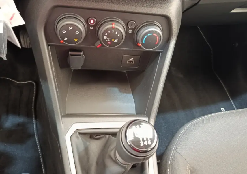 Gros plan sur la console centrale intérieure de la Dacia Sandero 2023, avec levier de vitesse manuel et commandes de climatisation.