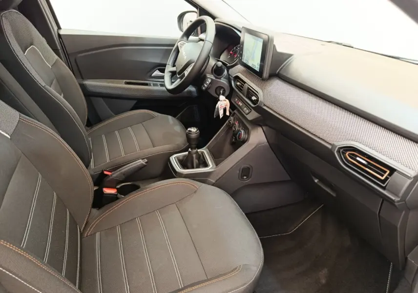Vue intérieure côté conducteur de la Dacia Sandero Expression EGO-G 100 2023, sièges noirs et tableau de bord avec écran tactile.
