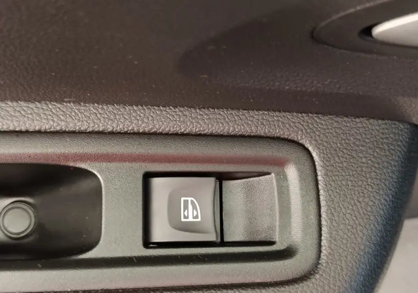 Bouton de commande de lève-vitre électrique sur porte intérieure d’une Dacia Sandero gris clair, version 2023.