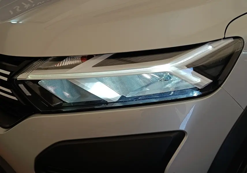 Gros plan sur le phare avant droit LED d'une Dacia Sandero gris clair 2023, soulignant son design moderne.