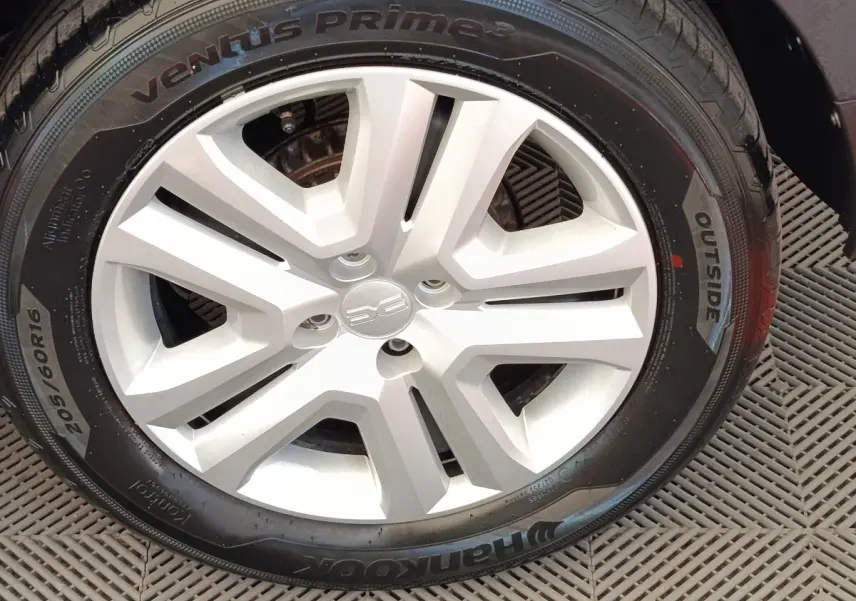 Gros plan sur la roue avant droite d'une Dacia Sandero gris clair avec jante en alliage au design moderne.